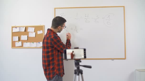 Bulgarian math teacher explaining equation written on whiteboard step by step to online class — Stock Video