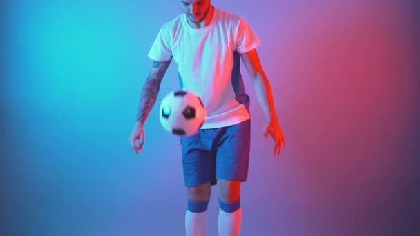 Slow motion van mannelijke professionele voetballer jongleren bal op been indoor studio — Stockvideo