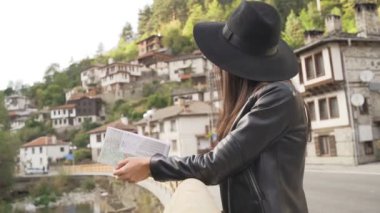 Bulgaristan 'ın Shiroka Laka kentinde şapka ve turistik haritaya sahip kadınlar. 