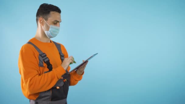 Klusjesman met tablet geïsoleerd op blauwe rug met kopieerruimte studio shot — Stockvideo