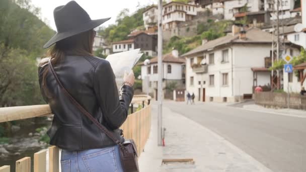 带着旅游地图和传统老房子背景的微笑女孩的背景图 — 图库视频影像