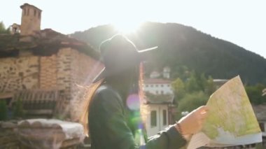 Güzel gezgin kız eski geleneksel Bulgar evlerinin yazı tipi ile haritasını çizdi. 
