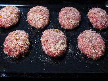 Et köftesi yarı bitmiş ürünler, ekmek kırıntıları ile serpilir, düzgünce fırında pişirmeden önce fırın tepsisine yayılır.