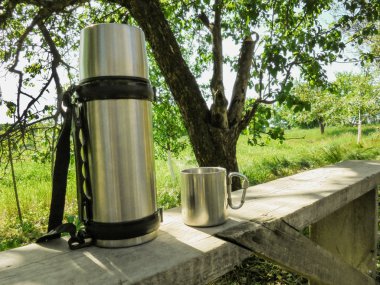 Yaz aylarında bahçede bir bankta paslanmaz çelik termos ve fincan standı