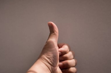 Baş parmağı yukarıda, siyah arkaplanda izole edilmiş.