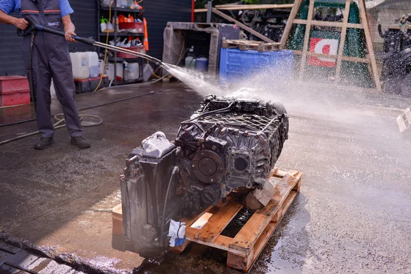 worker washes a truck engine