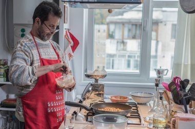 Adam mutfakta yemek pişiriyor.