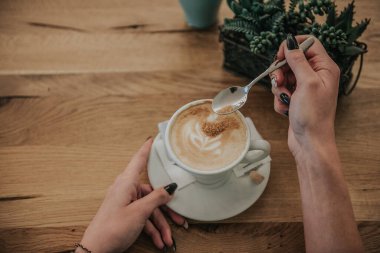 Elinde bir fincan kahve olan birine yakın dur.