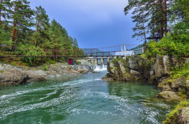 Güzel yaz dağ manzara Chemal Nehri, Altay Dağları, kayalık sahilleri, eski hidroelektrik santrali Barajı, bulutlu, yağmurlu hava arasında Rusya köprü üzerinde