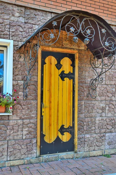 Wooden door, decorated with forging metal and casting canopy in exterior of contemporary building. Architecture elements for decor in retro style