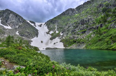 Yedi en temiz dağ Karakol göller, birinden bulunan Bagatash pass dibinde vadide Altay Dağları, Rusya. Kar dağ yamacında turkuaz göl - güzel bulutlu yaz manzara kaplı.
