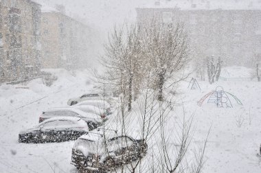 Kasabada şiddetli kar fırtınası var. Aralık ayında kar fırtınası sırasında, yerleşim alanındaki otoparka kar yağan araçlar. Kar yağarken kışın şehir manzarası. Kış hava tahmini ve trafik güvenliği kavramı