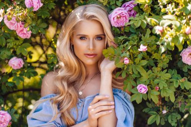 Çiçek açan ağaçtaki güzel sarışın kadın.