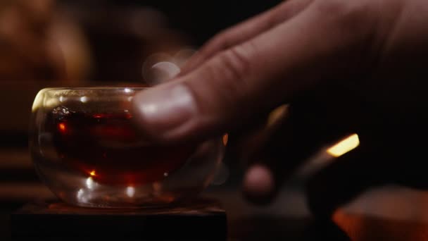 Cérémonie du thé, la main prend une petite tasse de thé en verre 