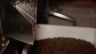 Kahverengi kavrulmuş kahve çekirdekleri büyük bir metal kase içine çelik bir kap düşüyor. Close. İçecek yapmak için mutfak ekipmanları. 