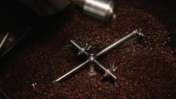 大きな鉄の車輪は非常にゆっくりと回り 大きなスチール容器に茶色の焙煎コーヒー豆を混合しています コーヒー製造機が作動している クローズ アップ — ストック動画