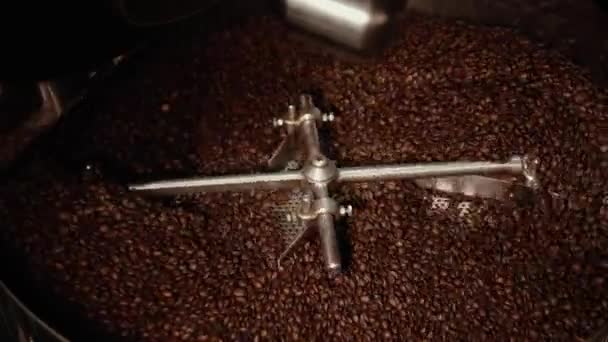 大きな鉄の車輪は非常にゆっくりと回り 大きなスチール容器に茶色の焙煎コーヒー豆を混合しています コーヒー製造機が作動している クローズ アップ — ストック動画