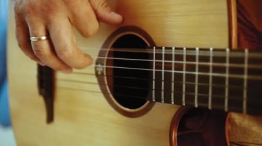 Müzisyen akustik gitar çalıyor. Altın yüzük ile parmaklar dizeleri dokunmadan. Belki de acemi gitarist ilk akorları öğrenme. Ya da belki müzik öğretiyorya ya da bir düğün grubunda çalıyordur..