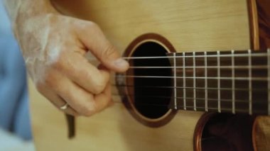 Müzisyen akustik gitar çalıyor. Altın yüzük ile parmaklar dizeleri dokunmadan. Belki de acemi gitarist ilk akorları öğrenme. Ya da belki müzik öğretiyorya ya da bir düğün grubunda çalıyordur..