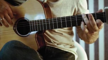 Müzisyen akustik gitar çalıyor. Altın yüzük ile parmaklar dizeleri dokunmadan. Belki de acemi gitarist ilk akorları öğrenme. Ya da belki müzik öğretiyorya ya da bir düğün grubunda çalıyordur..