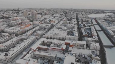 Yukarıdan büyük bir Rus şehrinin karlı çatıları ve sokakları. Kış, yollar, arabalar. Doğal aydınlatma, multikopter çekim.