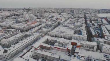 Yukarıdan büyük bir Rus şehrinin karlı çatıları ve sokakları. Kış, yollar, arabalar. Doğal aydınlatma, multikopter çekim.