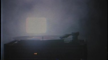 Bir müzik sever gramofonda bir albüm çalıyor. Eli vinil plakaya çoğalan bir kalem koyuyor. Kayıt çalar üstünde beyaz bir duman. Vhs vintage retro video.