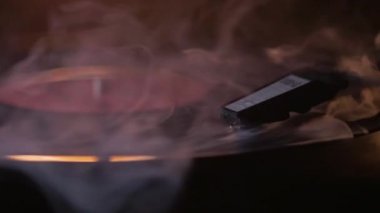 Oynatma kalemi vinil plaka üzerindedir. Albüm gramaphone'da çalıyor. Kalın beyaz bir duman kıvrılıyor..