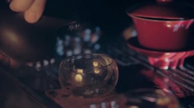 Çay ustası çay fincanına gaiwan 'dan çay dolduruyor ve çay tahtasına geri koyuyor. Bu bir çay seremonisi, Çin kültürünün önemli bir parçası..