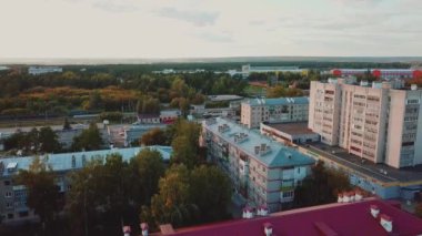 Yukarıdan demiryolu hatları olan görkemli bir şehir manzarası görebiliyoruz. Kırmızı çatıları olan birçok güzel evi olan bir yerleşim yeri var. Kamera yukarı çıkıyor..