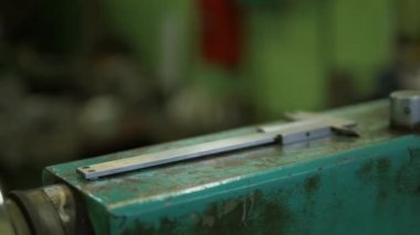 Bir cihazın metal yüzeyindeki demir kayma göstergesi. Bir fabrika işçisinin eli sürgülü kalibreyi alıyor..
