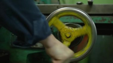 Bir fabrika işçisi yumruğuyla bir bitkinin üzerinde metal bir çarkla dönüyor. Etrafta bir sürü teçhizat ve ağır makineler görüyoruz..