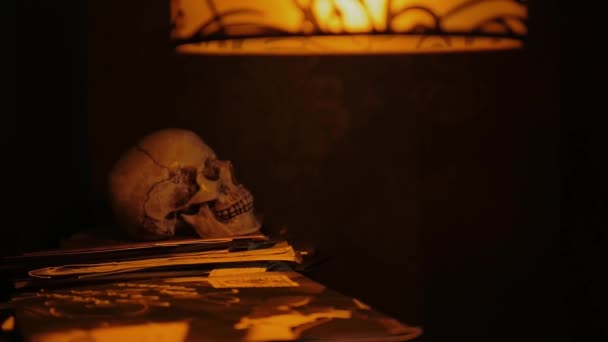 Gizemli Sarı Işıklandırmalı Cam Gölgelik Eski Yazmalarının Üzerinde Insan Kafatası — Stok video