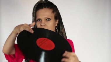 Kızıl saçlı, uzun gri afro örgülü ve koyu renk makyajlı gotik bir kız vinil plakla oynuyor. Vinil plak mağazası ya da müzik mağazası için yaratıcı bir konsept..
