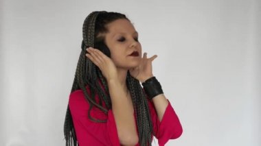 Kızıl saçlı, uzun gri afro örgülü ve koyu renk makyajlı gotik bir kız kulaklıklarla oynuyor. Müzik malzemeleri mağazası ya da müzik mağazası için yaratıcı bir konsept..