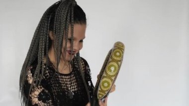 Uzun gri afro örgülü, koyu renk makyajlı gotik bir kız bir didjeridu 'ya bakıyor ve gülüyor. Müzik malzemeleri mağazası ya da müzik mağazası için yaratıcı bir konsept..