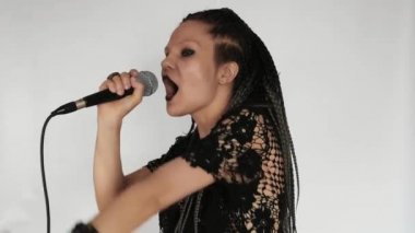 Uzun gri afro örgülü, koyu renk makyajlı gotik bir kız mikrofona şarkı söylüyor. O bir vokalist veya şarkıcı gibi davranıyor. Müzik mağazası için yaratıcı bir kavram ya da müzik teşvikleri.