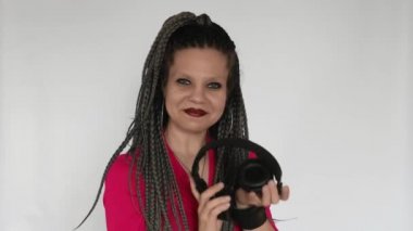 Kızıl saçlı, uzun gri örgü örgülü, koyu renk makyajlı gotik bir kız dev kulaklıklarla müzik dinliyor. Bu müzik aşığı sesten hoşlanıyor. Müzik malzemeleri mağazası ya da müzik mağazası için yaratıcı bir konsept..
