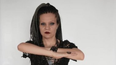 A gothic girl with long afro braids and a dark make up moves along the music, dances and strokes her hair.  A creative concept for cosmetics, afro hairstyle haidresser's or a fashion company.