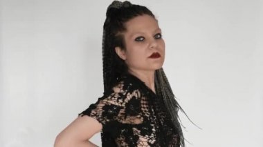 Siyah makyajlı ve şeffaf bluzlu garip gotik bir kız uzun afro örgülerini atıyor ve gizemli bir şekilde bakıyor. Kozmetik, afro saç stili haidreseri veya moda şirketi için yaratıcı bir konsept..