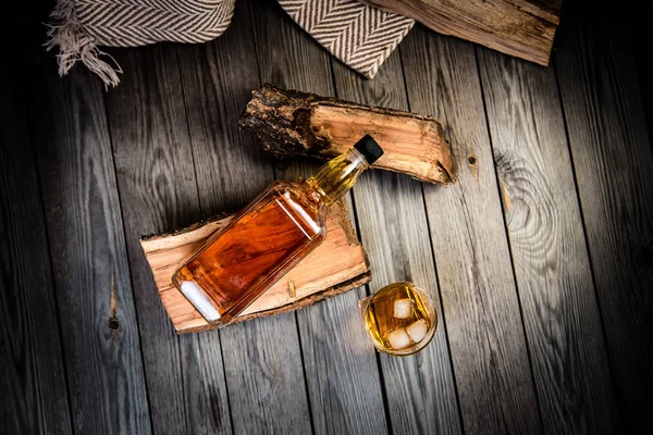 glass of whiskey and a bottle of whiskey on a wooden background