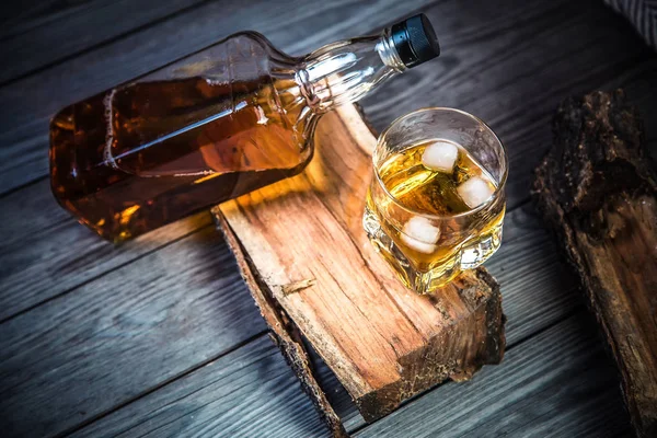 glass of whiskey and a bottle of whiskey on a wooden background