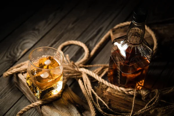 glass of whiskey and a bottle of whiskey on a wooden background