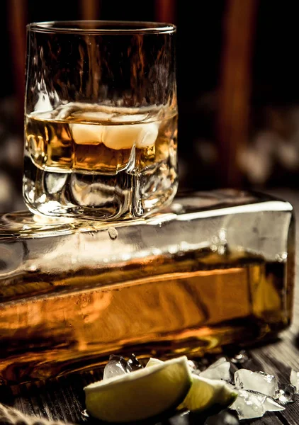 glass of whiskey, a glass of rum on a wooden bar counter