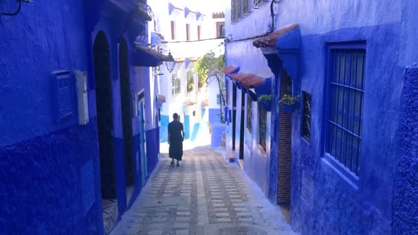 Een mannen lopen in de straat van de blauwe medina van de stad Chefchaouen in Marokko — Stockvideo