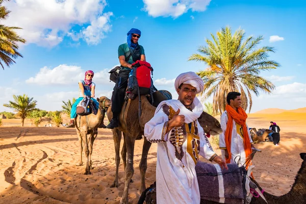 MERZOUGA, MAROCCO - 02 agosto: Guida maschile berbera in abito tradizionale che allena un giovane cammello maschio nell'Erg Chebbi — Foto Stock