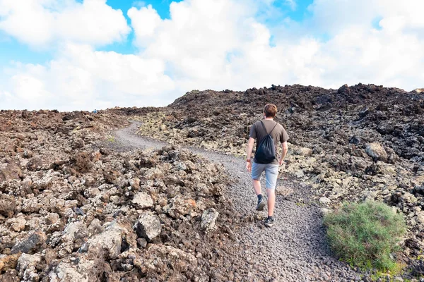 Un homme qui marche jette un paysage vulcanique avec champ de lave près d'un sentier touristique menant au vulcano Caldera Blanca, Lanzarote, Îles Canaries, Espagne — Photo