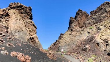 Krater Caldera de Los Cuervos, Timanfaya Milli Parkı, Lanzarote, Kanarya Adaları, 4 k görüntüleri video turist izini trek için yürüyen bir adam