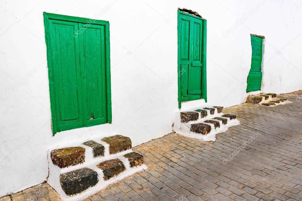 Typical tiny Canarian house with cactus garden and green doors or windows on the island of Lanzarote, Teguise, Canary Islands, Spain