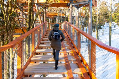 PUSTEVNY, CZECH REPUBLIC, FEBRUARY 16 Şubat 2019: Doğayı izleyen ve yeni bir ahşap gözetleme kulesinde veya gökyüzünde yürüyen tanımlanamayan turistler Pustevny, korunan manzara alanı Beskids 'da ağaçlarda yürüyorlar.